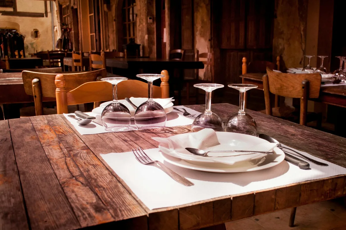 A rustic restaurant table set with wine glasses and cutlery invites guests to dine.